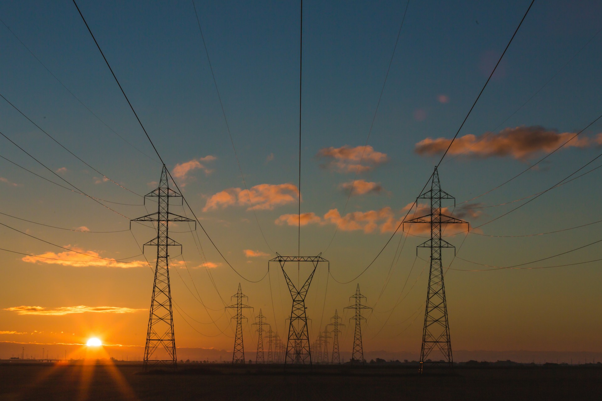 Power transmission towers silhouetted against a sunset sky