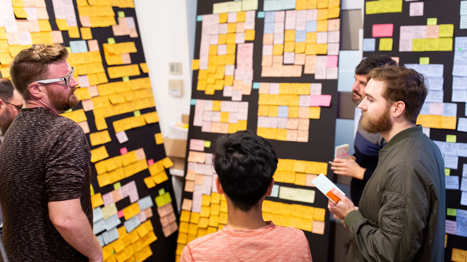 Team collaborating around boards covered in sticky notes during a product design sprint